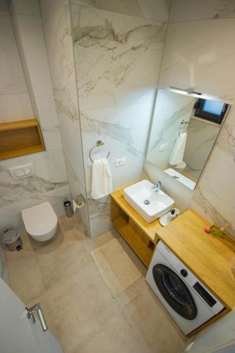 a bathroom with a sink and a toilet and a mirror at Apartmani LE-LU in Kaštela