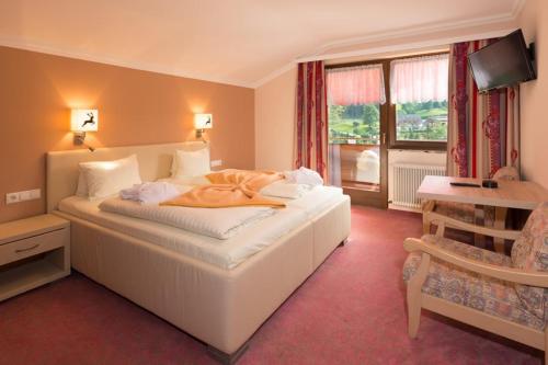 a bedroom with a large white bed and a window at Chalet Ferienhaus Hubertus in Schladming