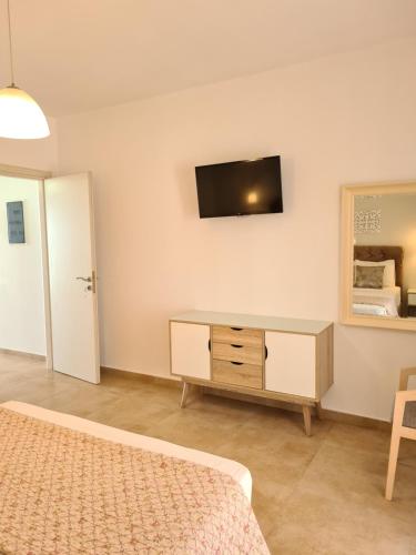 a bedroom with a dresser and a tv on the wall at Bella Mare Luxury Apartments in Kalamaki Heraklion