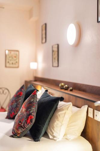a bed with four pillows on top of it at Garlande Hôtel Avignon Centre in Avignon