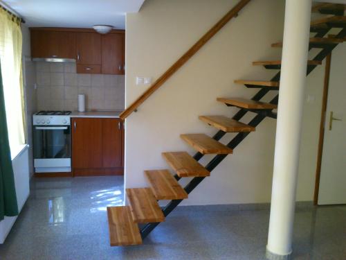 una escalera en una cocina con taburetes de madera en Agávé Apartman, en Sárvár