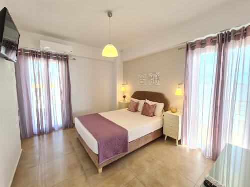 a bedroom with a large bed and some windows at Bella Mare Luxury Apartments in Kalamaki Heraklion