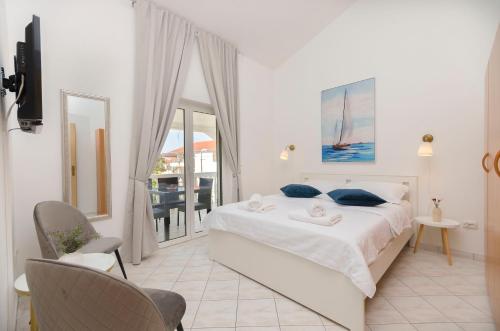 ein weißes Schlafzimmer mit einem Bett und einem Balkon in der Unterkunft Apartments Anton in Vodice
