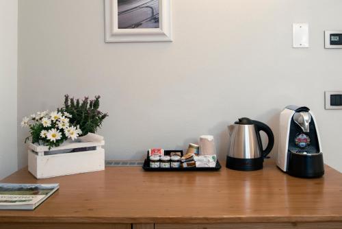 a table with a coffee maker and flowers on it at La Canonica Suite Apartments New Location in Trento
