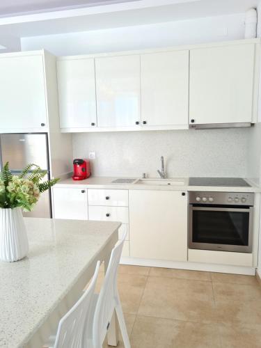 a white kitchen with white cabinets and a sink at Bella Mare Luxury Apartments in Kalamaki Heraklion