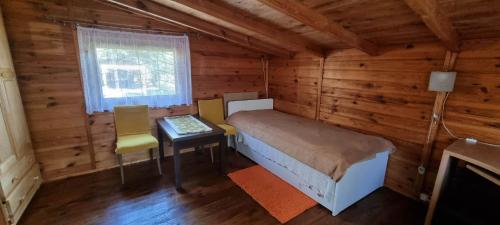 Dormitorio con cama y escritorio en una cabaña de madera en Domek "U Pszczelarza", en Golub-Dobrzyń