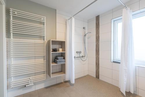 ein Bad mit einer Dusche und einer Glastür in der Unterkunft Waastwinj - 500m vom Strand in Utersum