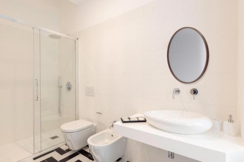 a white bathroom with a sink and a mirror at Metropolitan Rooms in Cagliari