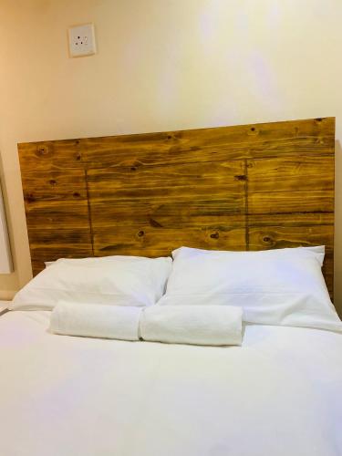 a bed with two white pillows and a wooden headboard at Seqonoka Villa Accommodation & Events Park in Berea Hills