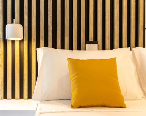 a yellow pillow sitting on top of a bed at Metropolitan Rooms in Cagliari