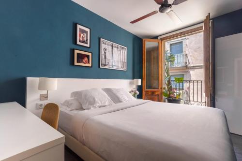 1 dormitorio con cama blanca y pared azul en Hostal Sol y K, en Barcelona