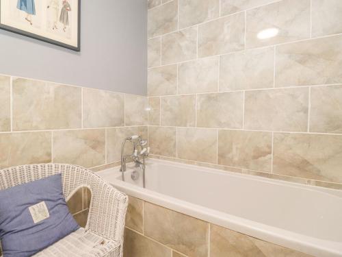 a bathroom with a white bath tub and a chair at West Farm Cottage in Morpeth