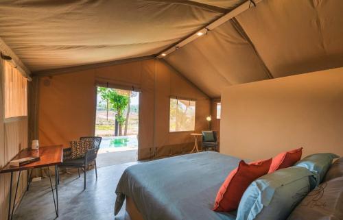 ein Schlafzimmer in einem Zelt mit einem Bett und einem Tisch in der Unterkunft Elephant View Camp in Ban Huai Thawai