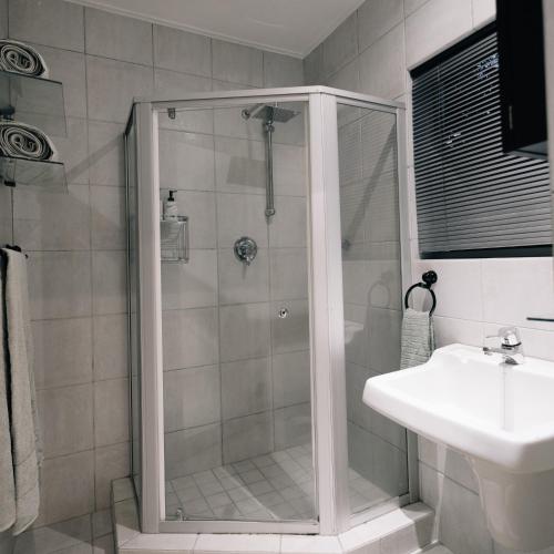 y baño con ducha y lavamanos. en Poolside Villa en Johannesburgo