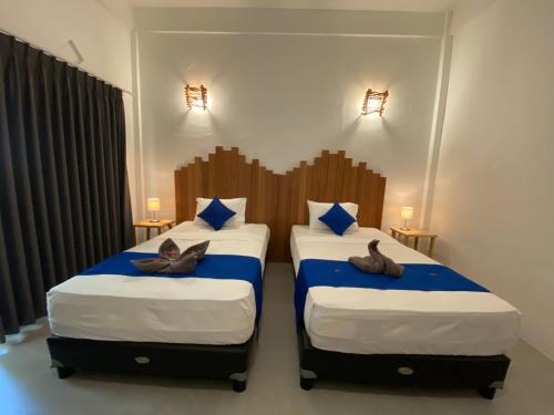 two beds in a hotel room with shoes on them at Living Trawangan Hotel in Gili Trawangan