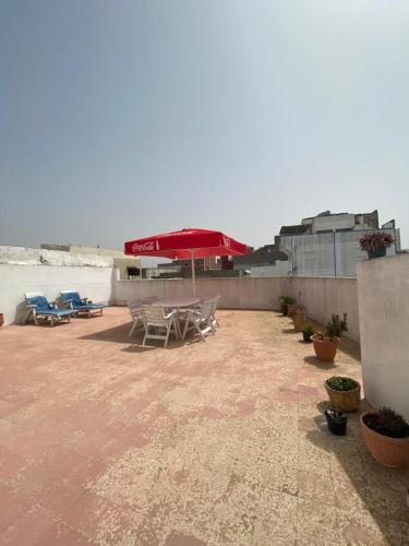 a patio with a table and a red umbrella at Maison Mina in Oualidia