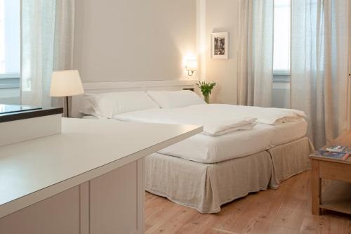 a white bedroom with a bed and a desk at La Canonica Suite Apartments New Location in Trento