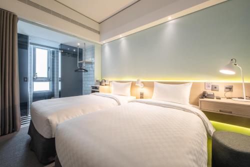 a hotel room with two beds and a window at Ramble Hotel in Taichung