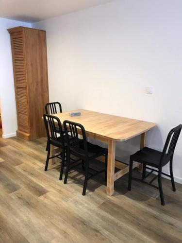 une table en bois entourée de quatre chaises noires dans l'établissement Appartement 2 chambres 5/7 pers proche centre commercial avec piscine, à Chamrousse