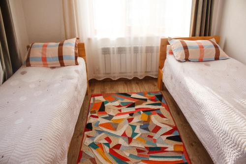 two twin beds in a room with a rug at Guest House Altyn Oimok in Bokonbayevo