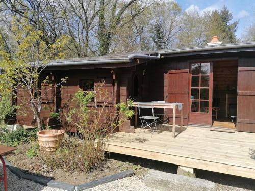 ein Haus mit einer Holzveranda und einer Holzterrasse in der Unterkunft Chalet en pleine nature au bord d'un étang in Lanvallay