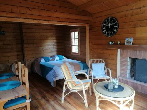 ein Schlafzimmer mit einem Bett und Stühlen in einer Blockhütte in der Unterkunft Chalet en pleine nature au bord d'un étang in Lanvallay