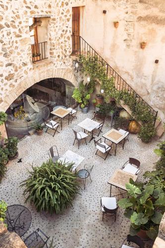 an outdoor patio with tables and chairs and a fireplace at Hotel Nord Boutique in Estellencs