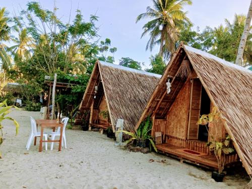 een resort met een tafel en stoelen op het strand bij Akoya Beach Sunset Camp in El Nido