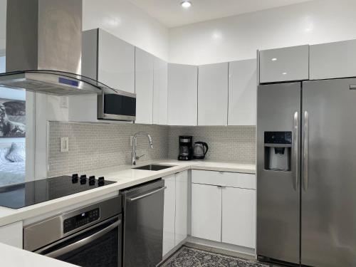 uma cozinha com armários brancos e um frigorífico de aço inoxidável em Modern & New,Excellent Location Miami em Miami