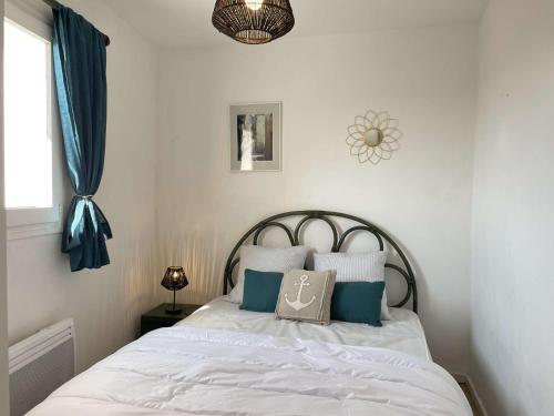 - une chambre avec un lit doté de draps blancs et d'oreillers bleus dans l'établissement Appartement 2 pièces avec balcon, proche plage - FR-1-224B-563, à LʼHerbaudière