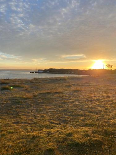a field with the sun setting in the background at Kostergården in Sydkoster