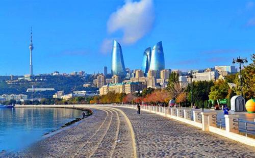 una persona caminando por una playa con una ciudad en el fondo en Essam Deluxe Hotel en Baku