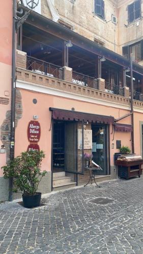 a building with a balcony and a piano on a street at Albergo Diffuso Locanda Specchio Di Diana in Nemi