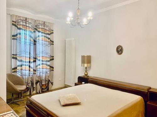 1 dormitorio con 1 cama, 1 silla y 1 lámpara de araña en Appartamento in campagna en Savigliano