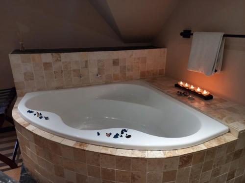 a large bath tub with candles in a bathroom at Mandalay Beach Guest House in Bloubergstrand