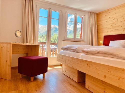 een slaapkamer met een bed en een raam met uitzicht op de bergen bij Hotel Capricorn in Zermatt