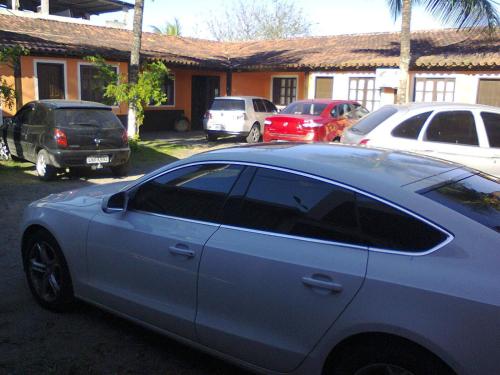 un coche aparcado en un estacionamiento frente a una casa en Pousada Enseada do Coqueiro, en Guarapari