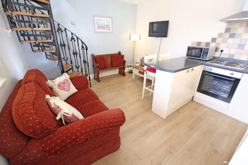 a living room with a red couch and a kitchen at Bakery Cottage Thirsk in Thirsk