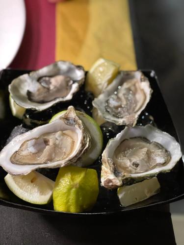 a plate of oysters and limes on a table at Sunrise Apt - Modern Studio Apt near the Beach in Birżebbuġa