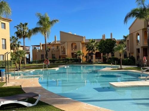 a large swimming pool with palm trees and houses at Panoramic Sea Views - Penthouse in Quartiers in Estepona
