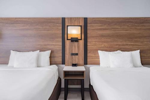 a hotel room with two beds and a night stand at Wingate by Wyndham Atlanta-Duluth in Duluth