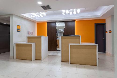 a lobby with orange and white walls and tables at La Quinta Inn & Suites by Wyndham Augusta Fort Eisenhower in Augusta