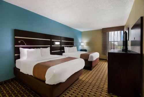 Quality Inn في هيوستن: سريرين في غرفة فندق بجدران زرقاء