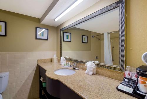 Quality Inn في هيوستن: حمام مع حوض ومرآة كبيرة