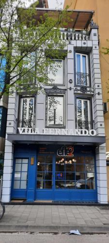 a building with blue doors and windows on a street at Hotel Villa Fernando Tirana in Tirana