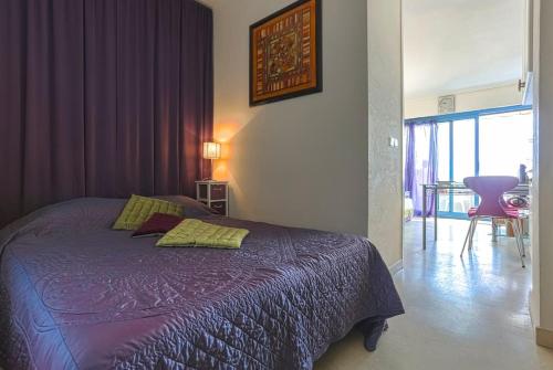 a bedroom with a bed with a purple comforter at French Riviera 1 bedroom on the beach facing Cannes in Théoule-sur-Mer