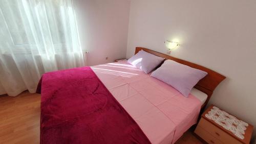 a bedroom with a large bed with a pink blanket at Apartment Nevenka in Krk