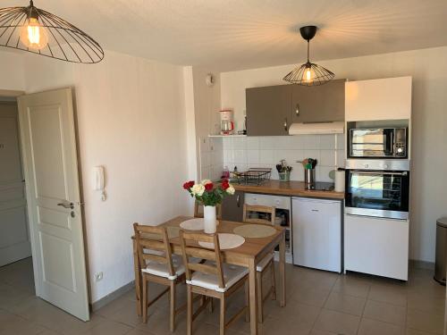 een keuken met een houten tafel en stoelen en een keuken met apparatuur bij Appartement 4 personnes in Narbonne