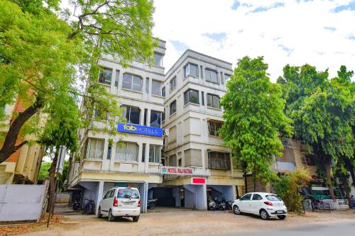 a building with two cars parked in front of it at FabHotel Raj Ratna, Ahmedabad in Ahmedabad