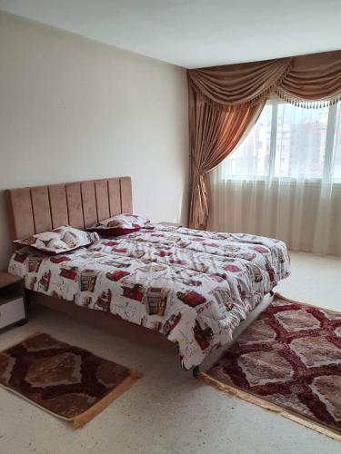 ein Schlafzimmer mit einem Bett mit einer Decke und einem Fenster in der Unterkunft Appartement confortable - Sfax centre in Sfax